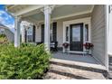 Inviting covered porch with stone steps, seating, and black front door at 243 E Wellesley Dr, Clayton, NC 27520
