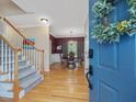 Inviting foyer with hardwood floors and staircase leading to dining room with decorative light fixture at 244 Elmcrest Dr, Holly Springs, NC 27540