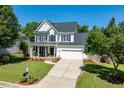 Beautiful two-story home with a manicured lawn, front porch swing, and a spacious driveway leading to a garage at 2933 Creek Moss Ave, Wake Forest, NC 27587