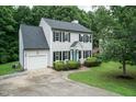 Traditional two-story house with a garage, manicured lawn, blue door, and mature trees creating a serene landscape at 3110 Trinness Dr, Durham, NC 27707