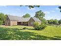 Exterior of a well-maintained brick home with a covered porch, lush greenery, and a serene pond view at 3537 Sweetgum Rd, Gibsonville, NC 27249