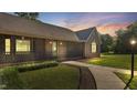 Charming brick home showcasing a covered front porch, lush green lawn, and a welcoming pathway at twilight at 3537 Sweetgum Rd, Gibsonville, NC 27249