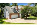 View of the home's garage and extended driveway surrounded by lush landscaping at 3720 Bridgeton Park Dr, Raleigh, NC 27612