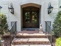 Elegant front entrance features a brick walkway, double doors, and sconces, enhancing the curb appeal at 5005 Lenoraway Dr, Raleigh, NC 27613