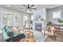 Bright living room featuring a fireplace, ceiling fan, and ample natural light from the multiple windows at 554 Beacon Ridge Blvd, Chapel Hill, NC 27516