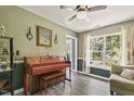 Bright living room featuring a piano, a ceiling fan, and natural light streaming through the large window at 601 Texanna Way, Holly Springs, NC 27540