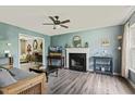 Cozy living room with a fireplace, hardwood floors, ceiling fan, and a glimpse into another room at 601 Texanna Way, Holly Springs, NC 27540