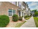 Exterior view of townhomes featuring well-maintained landscaping and covered entryway with white pillars at 6027 Kentworth Drive. Dr, Holly Springs, NC 27540