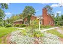 Landscaped brick home featuring a large chimney and walkway at 619 S Fifth St, Mebane, NC 27302