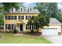 Charming yellow two-story home with black shutters and manicured lawn and white garage door at 1001 Kingsway Dr, Apex, NC 27502