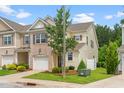 Townhouse featuring a well-maintained lawn, brick accents, a garage, and a charming tree in front at 1007 Epiphany Rd, Morrisville, NC 27560