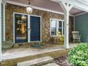 Inviting covered porch with stone accents, rocking chairs, and a blue front door entrance at 10101 Daviton Ct, Raleigh, NC 27615