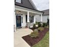 Inviting front porch featuring stone pillars, tasteful landscaping, and a beautiful front door with wreath at 108 Sweetbay Park, Youngsville, NC 27596