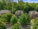 Aerial view of a traditional brick home surrounded by mature trees in a quiet, wooded neighborhood at 109 Aspenridge Dr, Holly Springs, NC 27540
