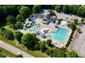 Aerial view of a community pool with water slides, seating, and a parking lot surrounded by lush trees at 109 Aspenridge Dr, Holly Springs, NC 27540