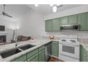 Open-concept kitchen and living area showcasing green cabinets, granite countertops, and stainless steel appliances at 11 Stone Village Ct, Durham, NC 27704