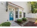 Charming townhome front entrance with a vibrant blue door, stylish fixtures, and lush green landscaping at 11710 Mezzanine Dr # 101, Raleigh, NC 27614