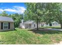 Exterior home view of a charming home, surrounded by green grass and mature trees at 1202 Kendall Dr, Durham, NC 27703