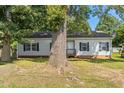 Single-story home with vinyl siding and dark shutters, shaded by a large tree in the front yard at 1442 Morningside Dr, Burlington, NC 27217