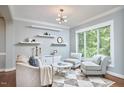 Cozy living room featuring a modern chandelier, floating shelves, and large window at 1601 Bellenden Dr, Durham, NC 27713