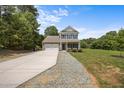 Charming two-story home featuring a brick facade, covered front porch, attached garage, and landscaped front yard at 2021 W Front St, Burlington, NC 27215