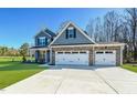 Charming two-story home featuring blue siding, stone accents, and a three-car garage with large driveway at 21 Abingdon Farms Dr, Selma, NC 27576