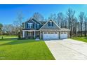 Charming two-story home featuring blue siding, stone accents, and a three-car garage on a manicured lawn at 21 Abingdon Farms Dr, Selma, NC 27576