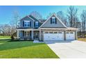 Charming two-story home featuring blue siding, stone accents, and a three-car garage on a manicured lawn at 21 Abingdon Farms Dr, Selma, NC 27576