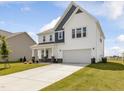 Two-story home with white siding, stone accents, covered porch, an attached two-car garage, and landscaped front yard at 218 Faith Avenue, Sanford, NC 27330