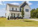 Two-story home with white siding, stone accents, covered porch, an attached two-car garage, and landscaped front yard at 218 Faith Avenue, Sanford, NC 27330
