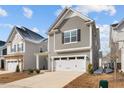 View of a charming gray two-story home with a white two-car garage, complemented by a well-maintained lawn at 2346 Mckenzie Ridge Ln, Apex, NC 27502