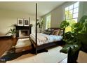 Bedroom featuring a four-poster bed, fireplace, hardwood floors, and plenty of natural light from large windows at 313 W Noble St, Louisburg, NC 27549