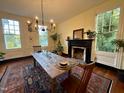 Traditional dining room with fireplace, wooden table set for dinner, and large windows offering outdoor views at 313 W Noble St, Louisburg, NC 27549