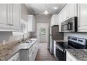 Galley kitchen featuring white cabinets, granite counters, and stainless steel appliances at 413 E Center St, Nashville, NC 27856