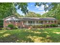 All-brick ranch home with a welcoming front porch, mature trees, and manicured landscaping at 5414 Ventoria Rd, Durham, NC 27712