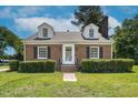 Traditional brick home boasts a cozy front yard with manicured hedges and dormer windows at 631 Park Ave, Rocky Mount, NC 27801