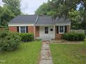 Charming single-story brick home with white trim, black shutters, and a well-maintained front lawn at 704 N King Charles Rd, Raleigh, NC 27610