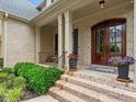 Covered front porch with brick steps, brick facade, and a wood door at 7906 Longleaf Branch Ct, Raleigh, NC 27612