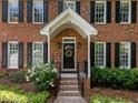 Close-up of a charming front door with brick steps, black railing, and manicured landscaping at 8004 Gabriels Bend Dr, Raleigh, NC 27612