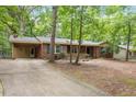 Traditional brick home with attached carport and charming front porch, nestled in a wooded lot with mature trees at 809 Valerie Dr, Raleigh, NC 27606