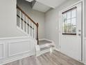 Welcoming entryway with staircase, wood-look flooring, wainscoting, and a bright, natural light filled door at 105 Leacroft Way, Durham, NC 27703