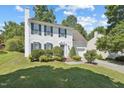 A charming white two-story home with green shutters, a well-kept lawn, and a driveway leading to the garage at 105 Leacroft Way, Durham, NC 27703