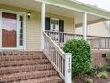 Inviting front porch with brick steps, a wooden railing, and the house number displayed on a post at 110 Westlake Dr, Wendell, NC 27591