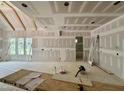 A spacious living room with unfinished walls and big bright windows at 155 Cherry Bark Dr, Youngsville, NC 27596