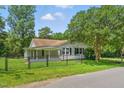 Quaint one-story home with shuttered windows, covered porch, and a mature shade tree in a fenced yard at 16 S Church, Coats, NC 27521