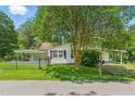 Quaint one-story home with shuttered windows, covered porch, and a mature shade tree in a fenced yard at 16 S Church, Coats, NC 27521