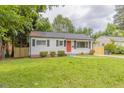 Charming single-story home featuring a well-maintained lawn and an inviting orange front door at 1708 Forest Rd, Durham, NC 27705