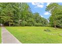 Large grassy yard surrounded by mature trees under a partly cloudy sky, conveying a sense of open space at 201 Cobblestone Dr, Chapel Hill, NC 27516