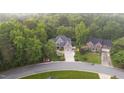 An aerial showcases the home nestled amongst mature trees, a serene setting, and a circular driveway at 3024 Weston Ct, Burlington, NC 27215