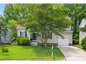 Charming two-story home boasts a well-manicured lawn and attached garage, framed by mature trees at 304 Gold Point Dr, Cary, NC 27519